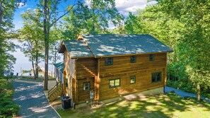 A wooden cabin with a sloped roof, a front porch, and a small front yard. - Waterfront Cabin! Dock, Crab, Paddle, Kayak, Outdoor Movie, Karaoke, and More! (Heathsville)