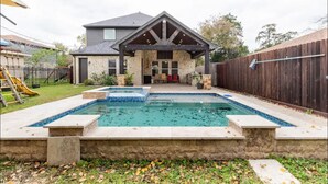 Un jardin avec une piscine, une terrasse couverte et une clôture en bois.