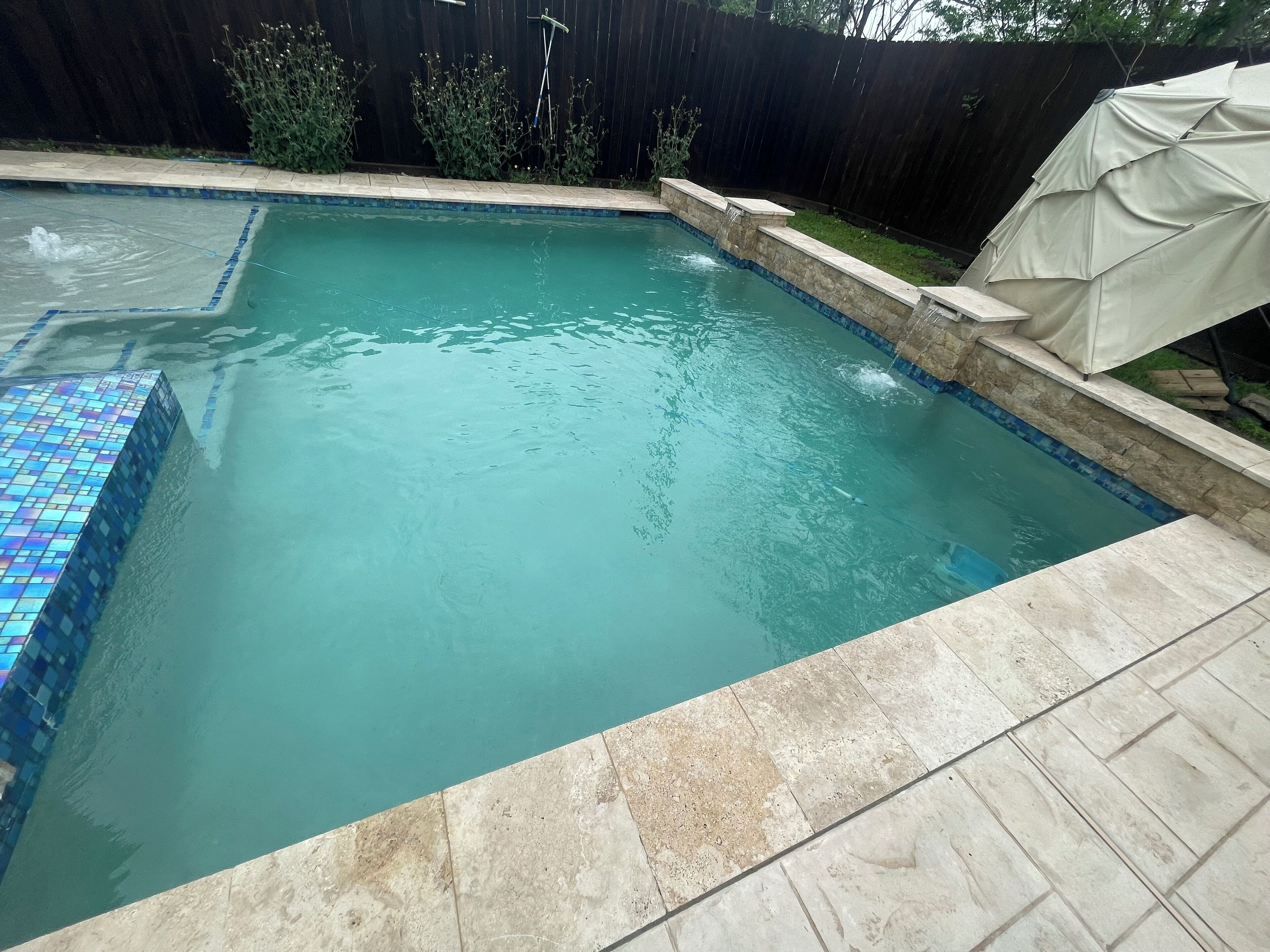Una piscina rectangular con borde de azulejos y orilla de piedra.