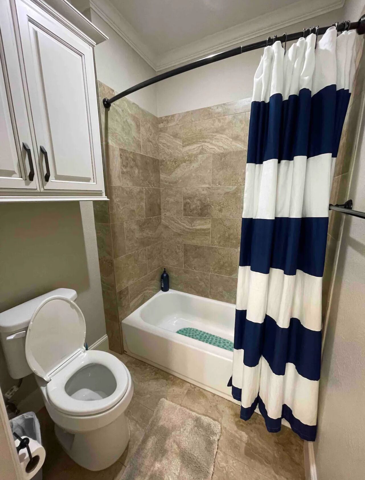A bathroom with a toilet, a bathtub with a shower curtain, and tiled walls.