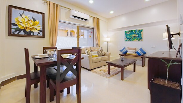 A modern living room with a dining area, a sofa set, a coffee table, and a TV stand with a plant. - F3 Apartment, 2-Bedroom (F3) (Placencia Village)