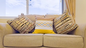 A beige sofa with two patterned cushions and a single geometric cushion. - F3 Apartment, 2-Bedroom (F3) (Placencia Village)