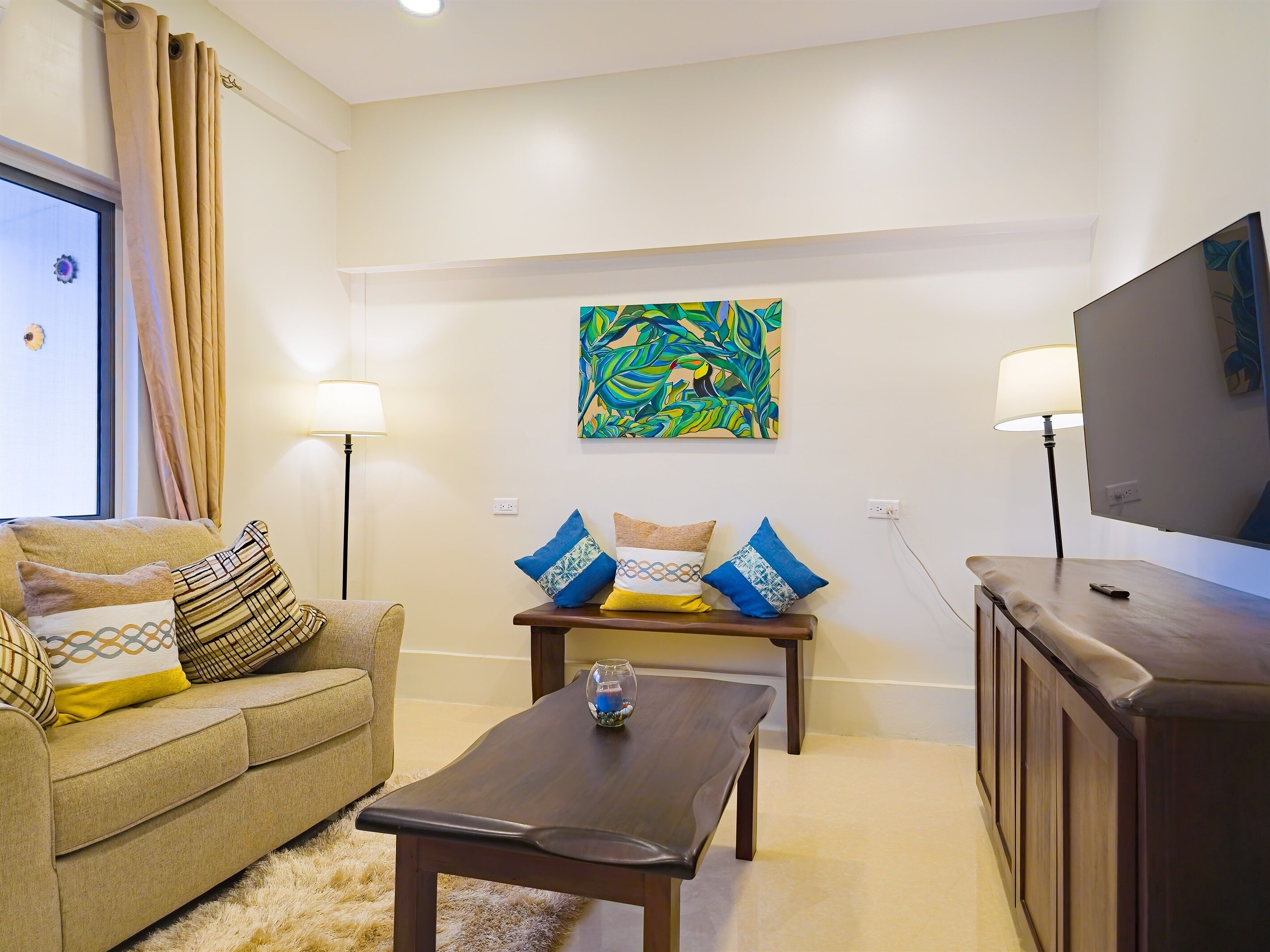 A living room with a sofa, a coffee table, a TV, and a painting on the wall.
