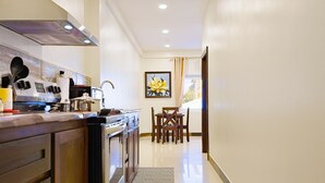 A modern kitchen with a stove, oven, and a dining area with a table and chairs. - F3 Apartment, 2-Bedroom (F3) (Placencia Village)