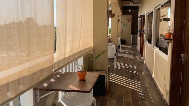 Un pasillo con una mesa y sillas de madera, adornos colgantes y suelo de baldosas.