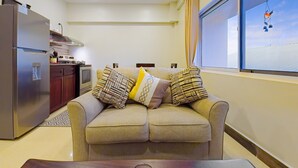 Una sala de estar moderna con un sofá, una mesa de comedor y una cocina con refrigerador y estufa.