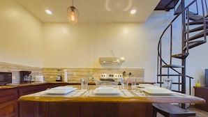 A modern kitchen with a central island, built-in appliances, and a spiral staircase.