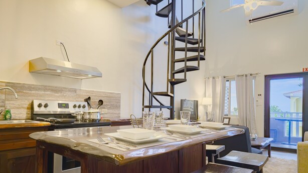 A modern kitchen with a central island, a built-in oven, and a spiral staircase.