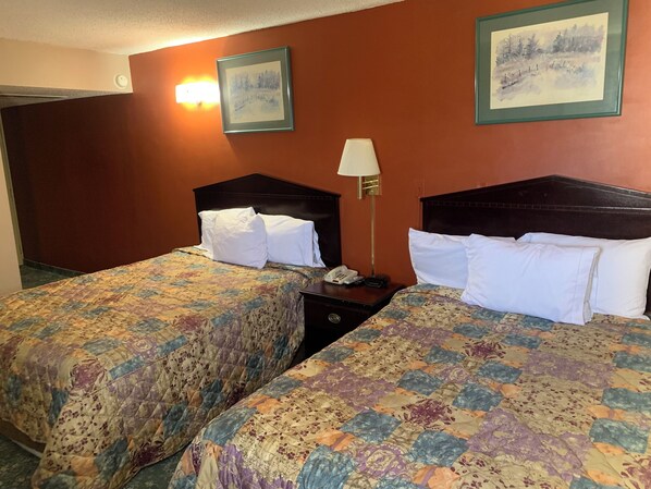 A hotel room with two beds, each with a floral-patterned bedspread, a bedside lamp, and a telephone on the nightstand. - Hotel Jackson (Macomb)