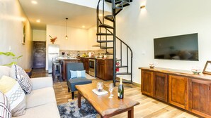 A modern living room with a sofa, coffee table, and a spiral staircase leading to an upper level. - T4 Suite, 2-Bedroom (T4) (Placencia Village)