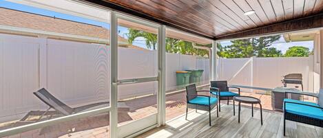 Une terrasse extérieure dotée d’un plafond en bois, de portes-fenêtres coulissantes et de mobilier d’extérieur.