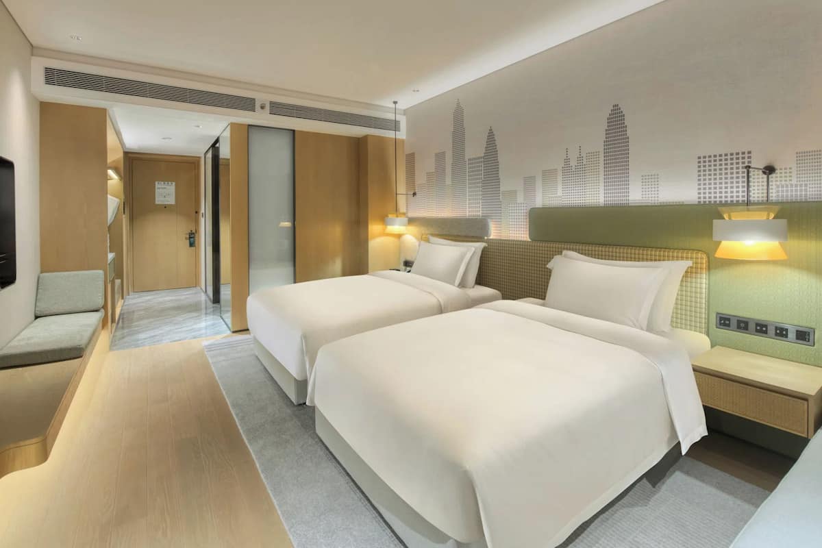 A hotel room with two beds, a flat-screen TV, a cityscape mural, and a modern design.