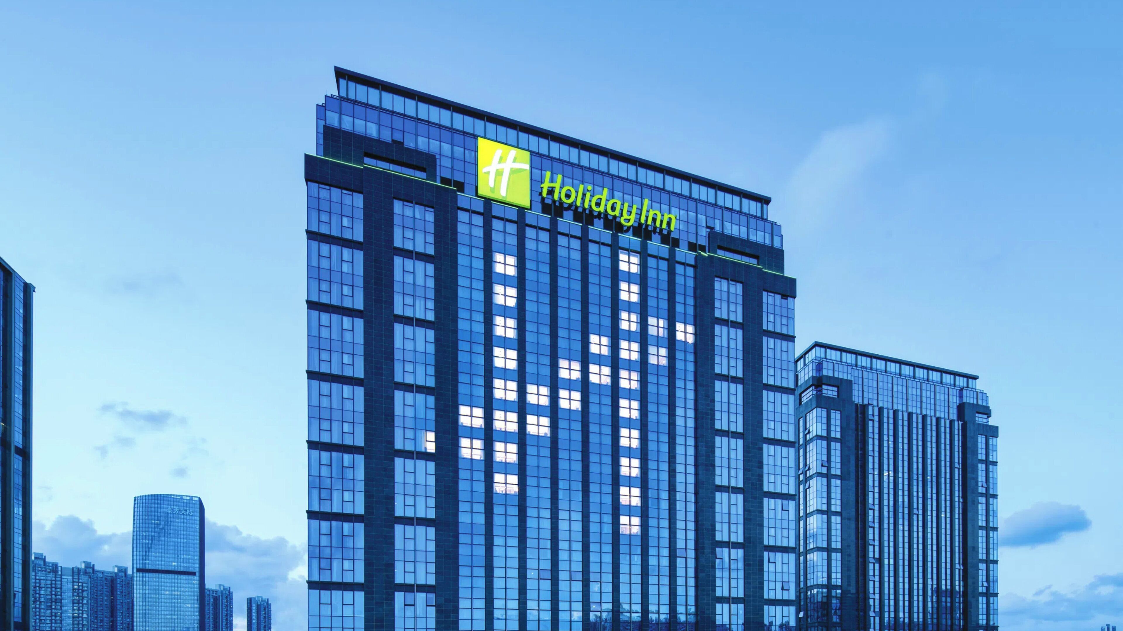 Un hôtel Holiday Inn moderne, doté d’une façade en verre et d’un logo bien visible.