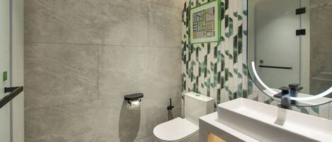 A modern bathroom with a toilet, bidet, and a sink with a mirror.