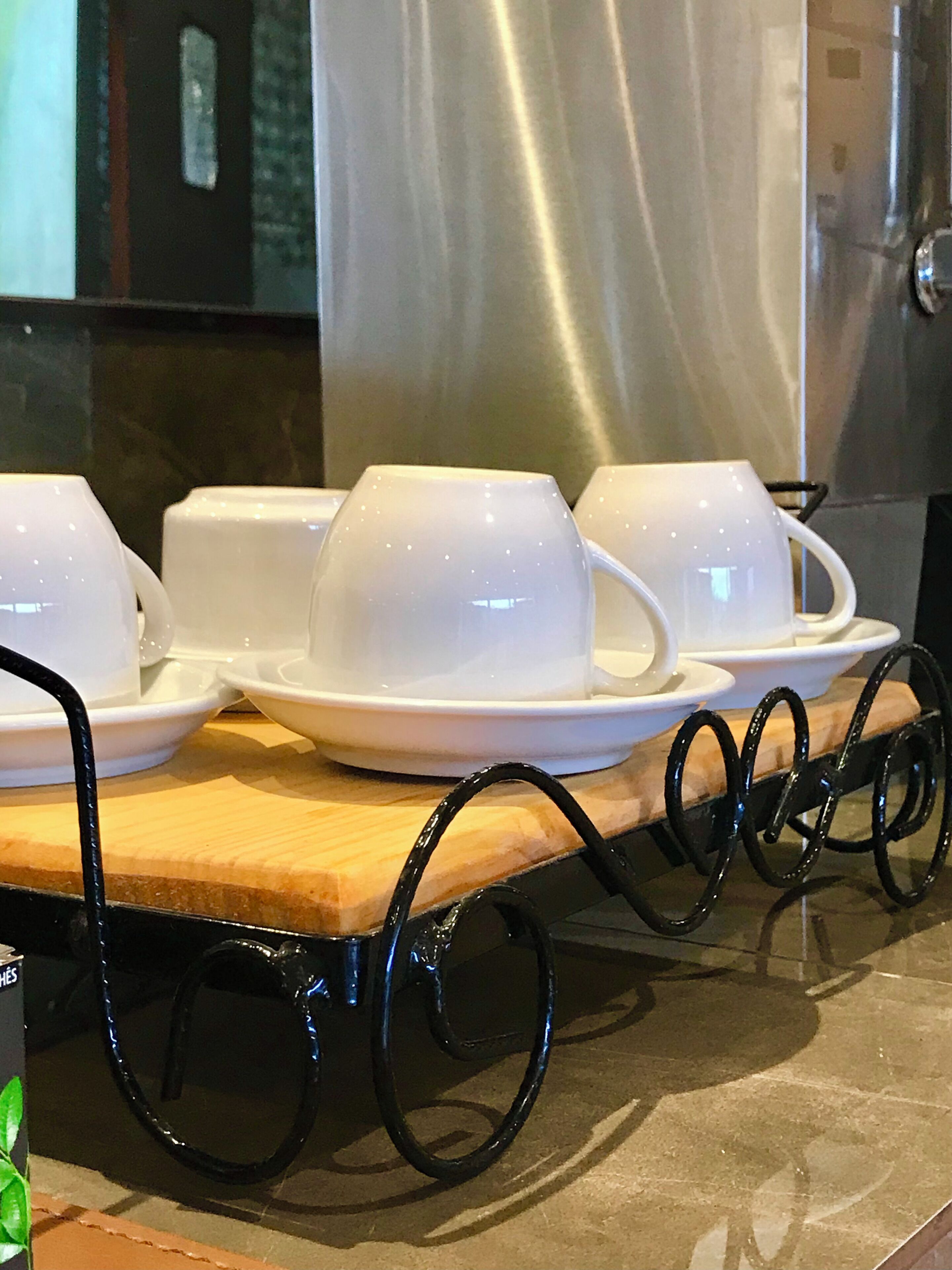 Un juego de tazas y platillos blancos sobre una bandeja de madera con asas negras.