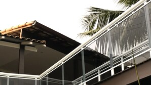 A modern building with a glass balcony, yellow walls, and a palm tree. - Pousada Gente Bonita La Mansion (Búzios)
