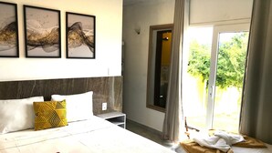 A hotel room with a large bed, a nightstand, a mirror, and three framed pictures on the wall. - Pousada Gente Bonita La Mansion (Búzios)