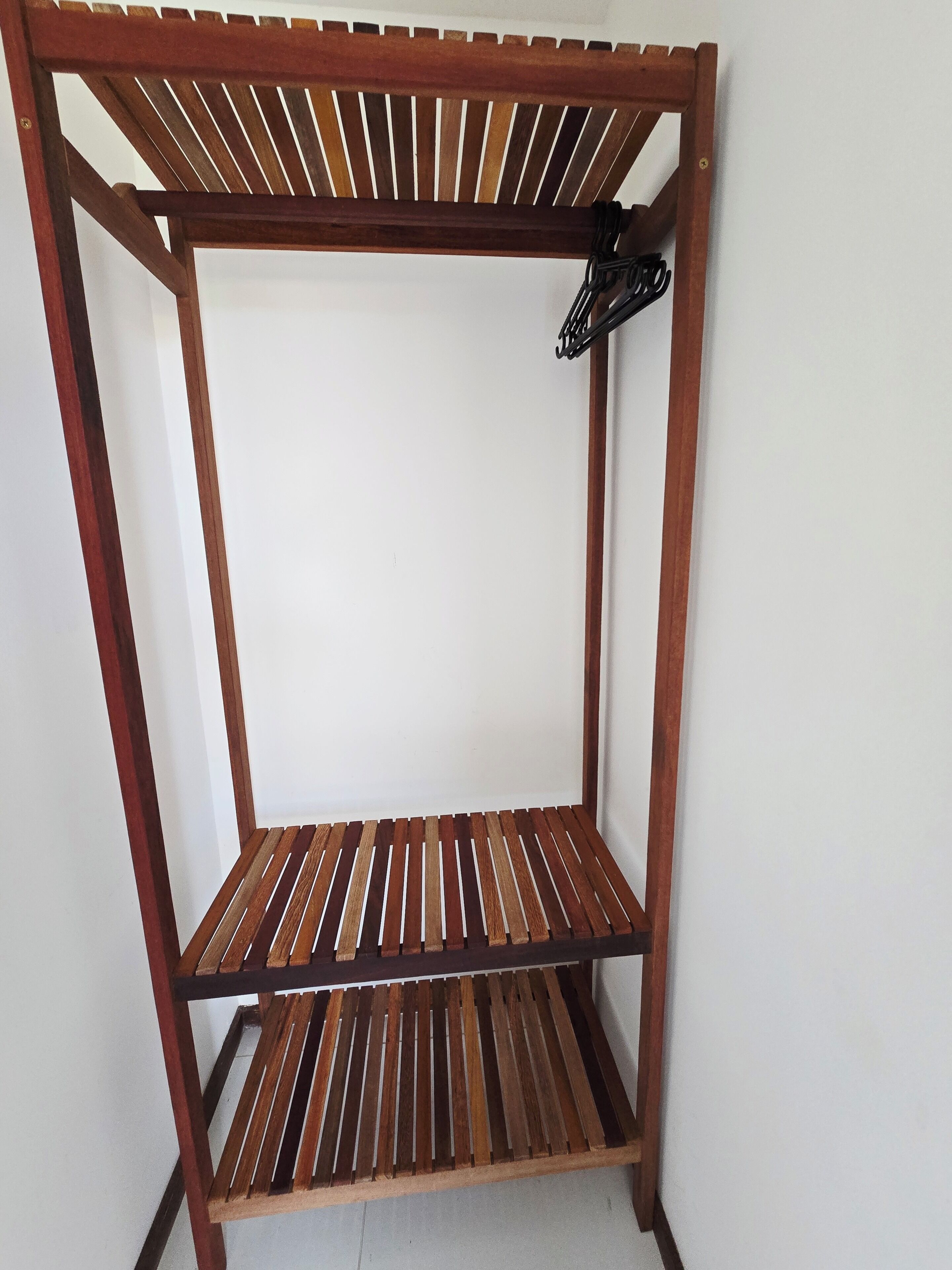 Una scaffalatura in legno a più ripiani con un gancio metallico.