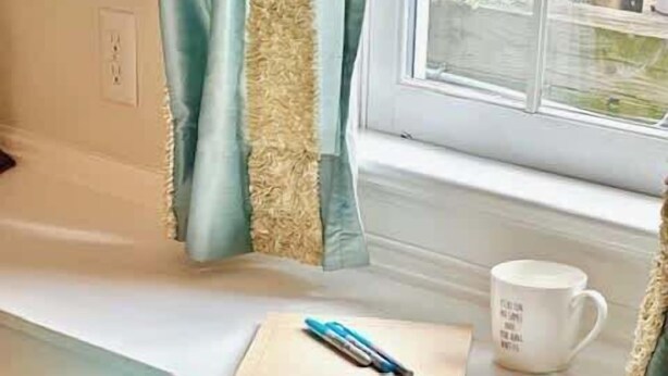Ein blaugrüner Sessel, ein weißer Schreibtisch, eine blaue Tasse und ein Stift auf dem Schreibtisch.