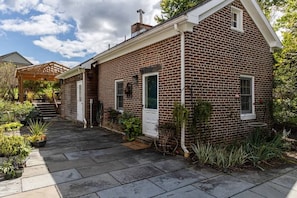 Une maison en briques avec un porche couvert, une porte d’entrée et une petite fenêtre.