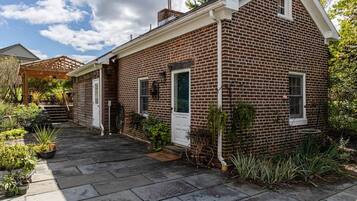 A brick house with a covered porch, a front door, and a small window.