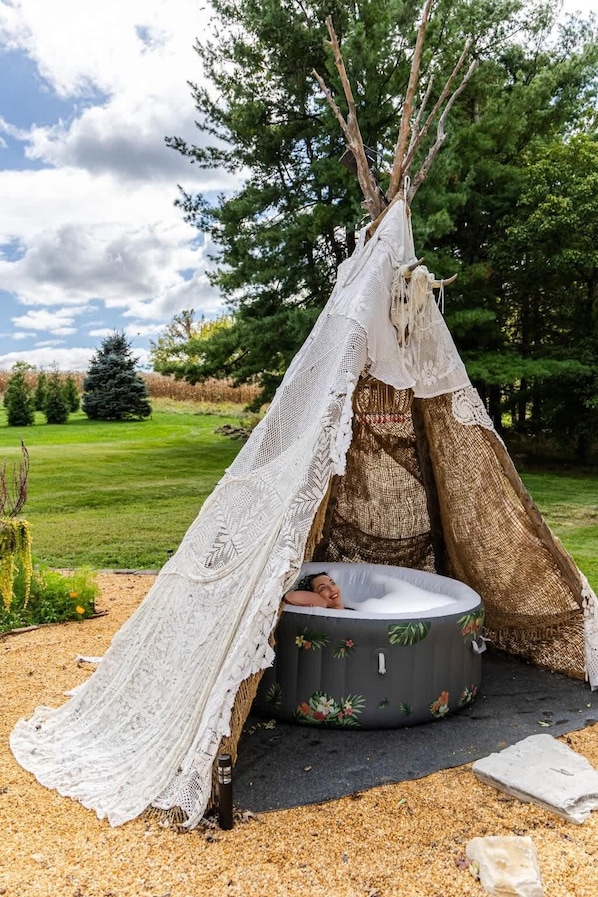 A teepee with a sleeping area inside, surrounded by a natural landscape.