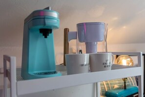 Een keukenhoek met een koffiezetapparaat en een koffiekan op een plank.
