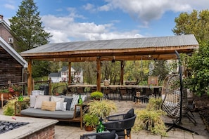 An outdoor patio area with a wooden pergola, seating arrangements, and potted plants.