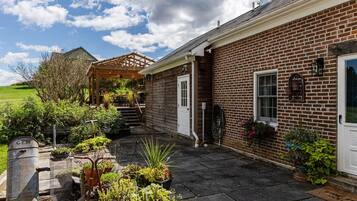 A brick house with a covered porch, a front door, and a small garden area with potted plants.