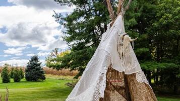A teepee with a sleeping area and a hot tub.