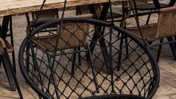 A rustic outdoor dining area with a wooden table and wicker chairs.