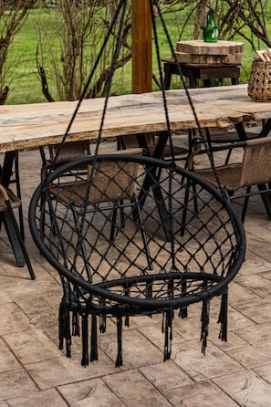 Un espace de restauration extérieur de style rustique, avec une table en bois et des chaises en osier.