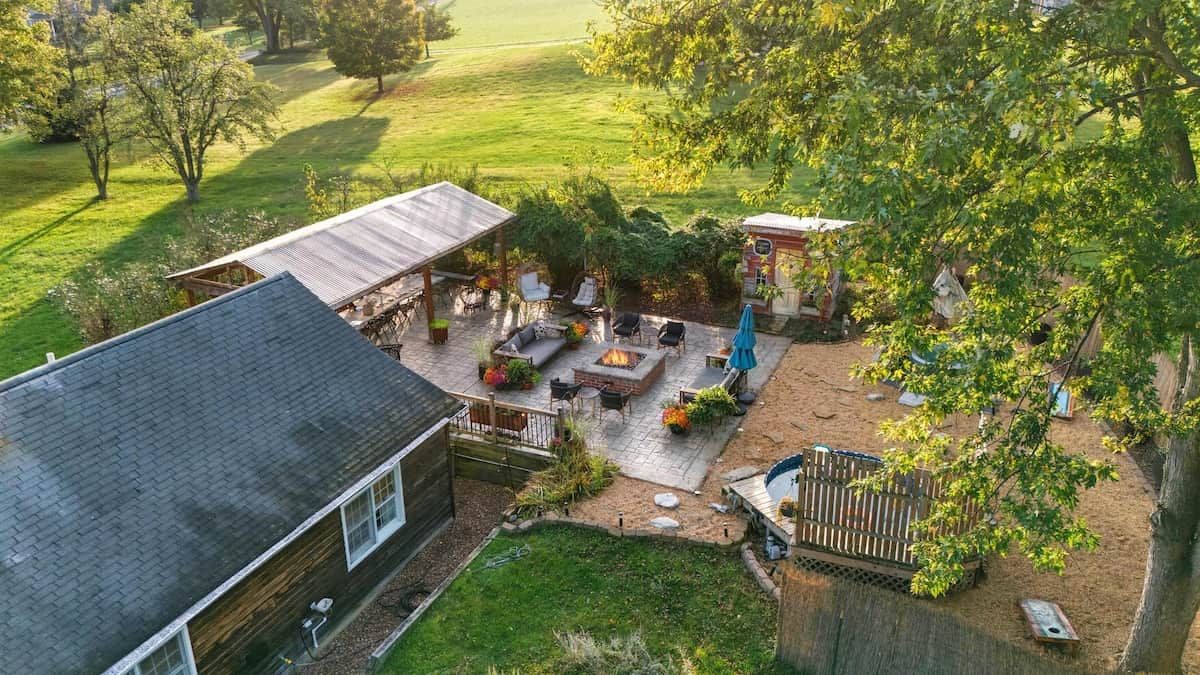 A backyard with a patio, outdoor seating, a fire pit, and a small shed.