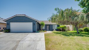 A residential house with a garage, a driveway, and a well-maintained lawn with a tree.