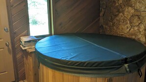 Un bain à remous dans une pièce en bois, avec un mur en pierre et une fenêtre.