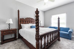 A bedroom with a four-poster bed, a nightstand, a blue sofa, and a ceiling fan. - Escape to our stunning pool home retreat in Vero Beach, Florida!
 (Vero Beach)