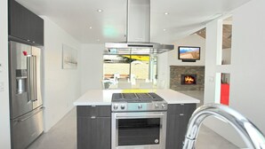 A modern kitchen with a built-in oven, a stainless steel refrigerator, and a stone fireplace. - Palms Spring Doering Vista Estate (Palm Springs)