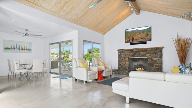 A spacious living area with a stone fireplace, white sofas, and a dining table with chairs. - Palms Spring Doering Vista Estate (Palm Springs)