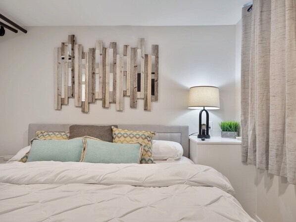 A bedroom with a bed, pillows, a nightstand, a lamp, and a wall decoration. - Great location, PET friendly, FREE parking, quiet neighborhood, near Colleges (Saint Paul)