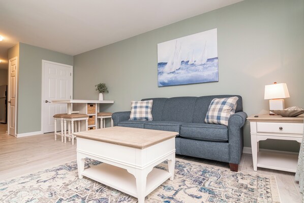 A living room with a grey sofa, a white coffee table, and a blue patterned rug.