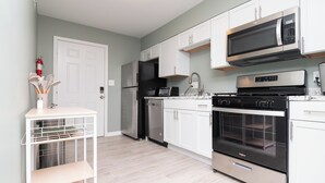 Une cuisine moderne avec des meubles blancs, un réfrigérateur en acier inoxydable, un four à micro-ondes, un four traditionnel et un lave-vaisselle.