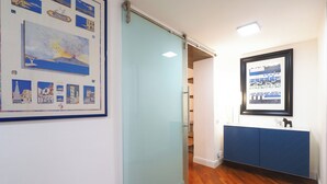 A hallway with a glass door, a framed map of Naples, and a blue cabinet with a small dog figurine. - C23 - Premium Apartment in Milan (Milano)