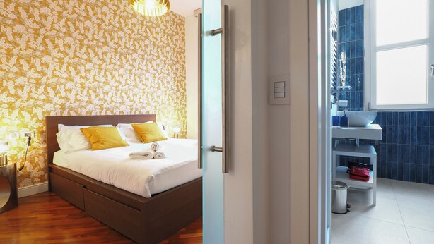 A bedroom with a wooden bed, a bathroom with a blue tiled wall, and a window. - C23 - Premium Apartment in Milan (Milano)