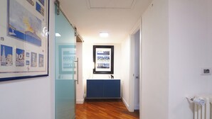 A hallway with wooden flooring, a glass partition, a blue cabinet, and a framed picture on the wall. - C23 - Premium Apartment in Milan (Milano)