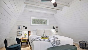 A bedroom with a bed, bedside tables, a chair, a bench, a ceiling fan, and a window. - Brand NEW build. A-frame 2bed+/2bath. Nature paradise. Pepin, WI. (Pepin)