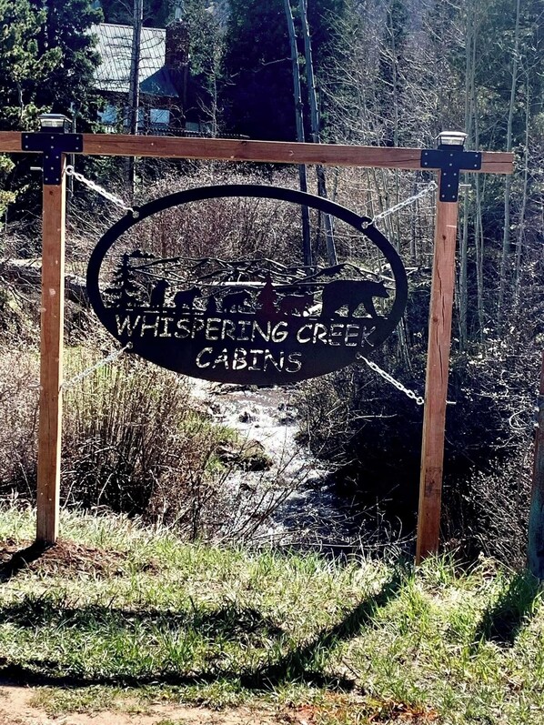 A sign with the text "Whispering Creek Cabins" indicating a location or destination.