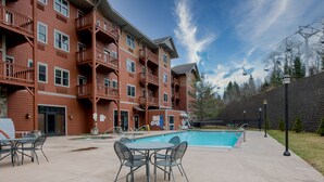 A multi-story building with balconies, a swimming pool, outdoor seating, and a ski lift in the background. - The ultimate resort experience. Pool, hot tub, sauna, steam room, exercise room. (Hunter)