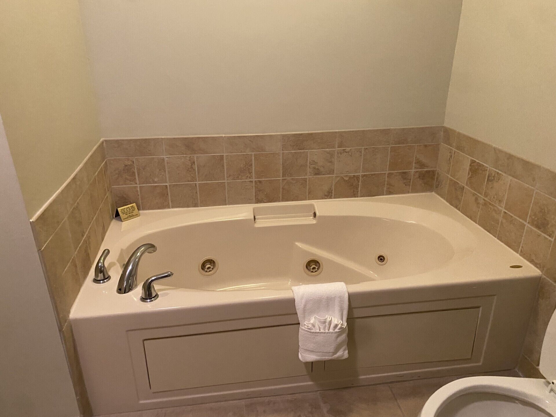 A bathroom with a large bathtub, two faucets, and a toilet.