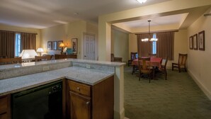 A kitchen with a dishwasher, a dining area with a table and chairs, and a hallway leading to another room. - The ultimate resort experience. Pool, hot tub, sauna, steam room, exercise room. (Hunter)