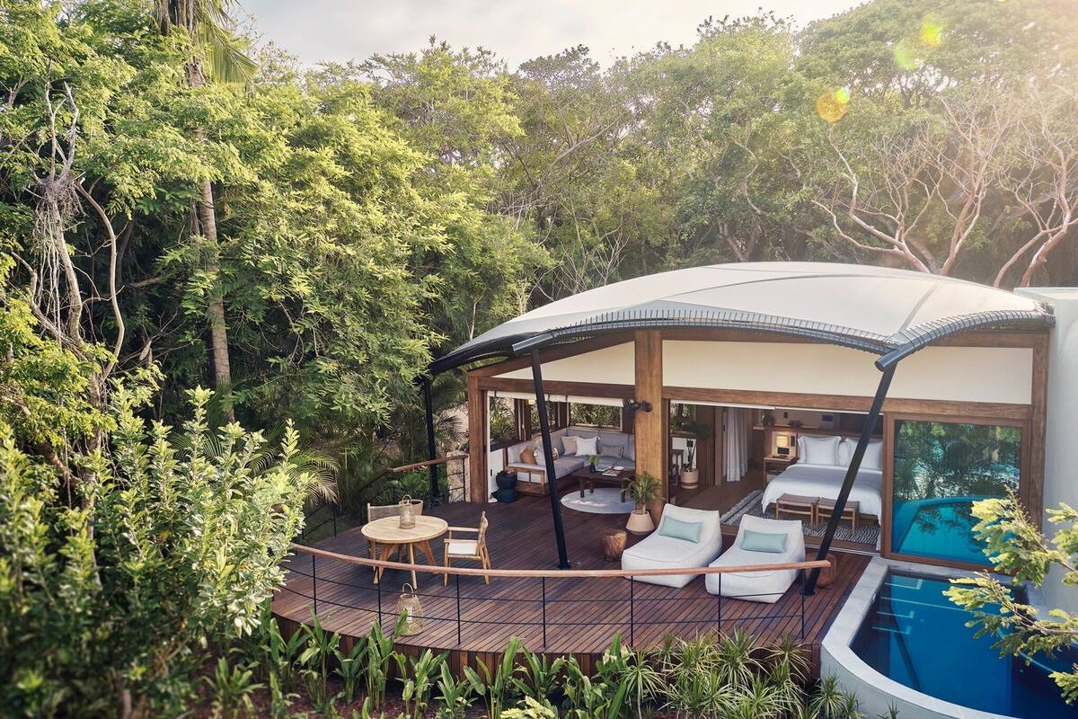 A luxurious outdoor lounge area with a pool, wooden deck, and seating arrangements.